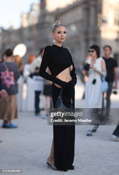 Leonie Hanne is seen outside Mugler show wearing black triangle Prada earrings, black asymmetric Mugler dress with open front, black leather Mugler...