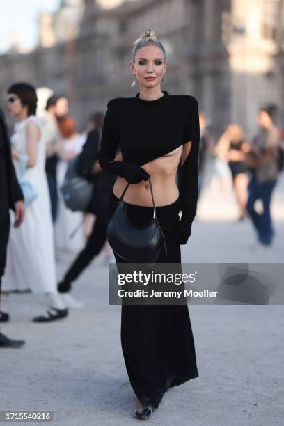 Leonie Hanne is seen outside Mugler show wearing black triangle Prada earrings, black asymmetric Mugler dress with open front, black leather Mugler...