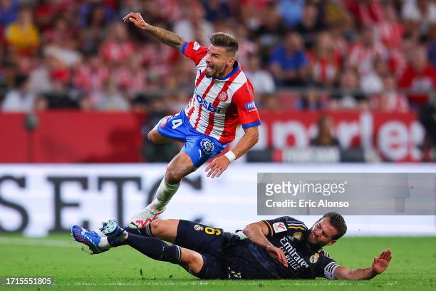 Portu of Girona FC is tackled by Nacho Fernandez of Real Madrid during the LaLiga EA Sports match between Girona FC and Real Madrid CF at Montilivi...