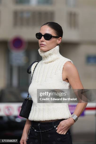 Sophia Roe wears sunglasses, a white sleeveless turtleneck wool knit top, outside Chanel, during the Womenswear Spring/Summer 2024 as part of Paris...