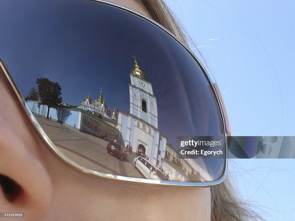 Chapel building reflected in a woman's sunglasses lens