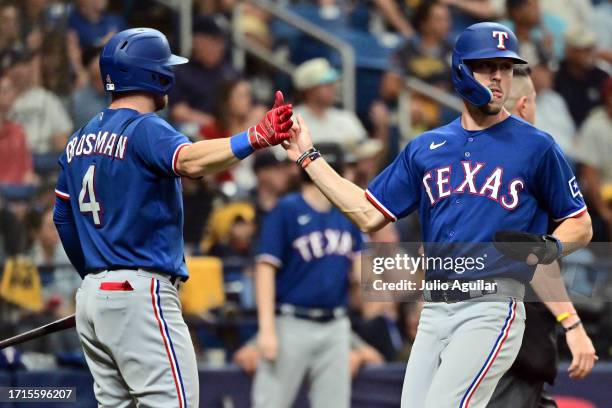 Evan Carter celebrates with Robbie Grossman of the Texas Rangers after scoring in the sixth inning against the Tampa Bay Rays during Game One of the...