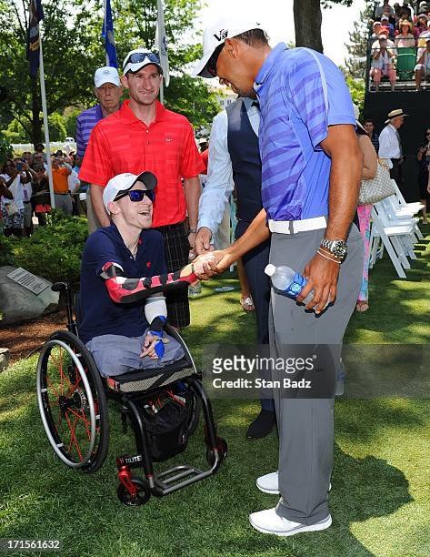 Wounded Warrior Brendan Marrocco is greeted by Tiger Woods on the first tee during the patriotic opening ceremony for the AT&T National at...