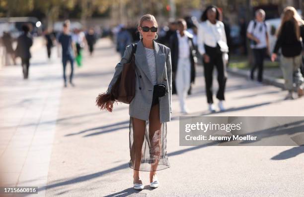 Fashion Week Guest is seen wearing a white tshirt with a long black tulle skirt, short black pants underneath, combined with a grey blazer, a...