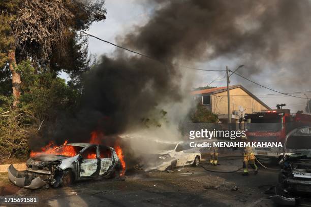 Firefighters douse a car blaze in the southern Israeli city of Ashkelon after a rocket attack from Gaza on October 9, 2023. Stunned by the...