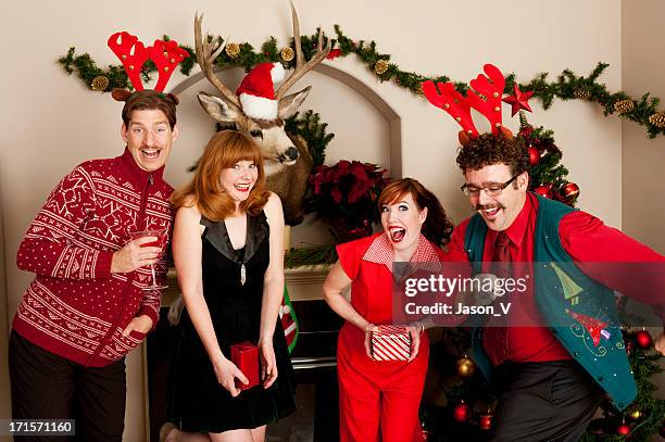 people in festive clothing smiling during a holiday party - ugly christmas sweater party stock pictures, royalty-free photos & images