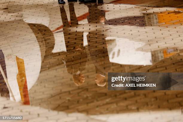 The reflections of German Chancellor Olaf Scholz and his partner Britta Ernst are seen in water puddle as they arrive at the Airbus plant in Hamburg,...