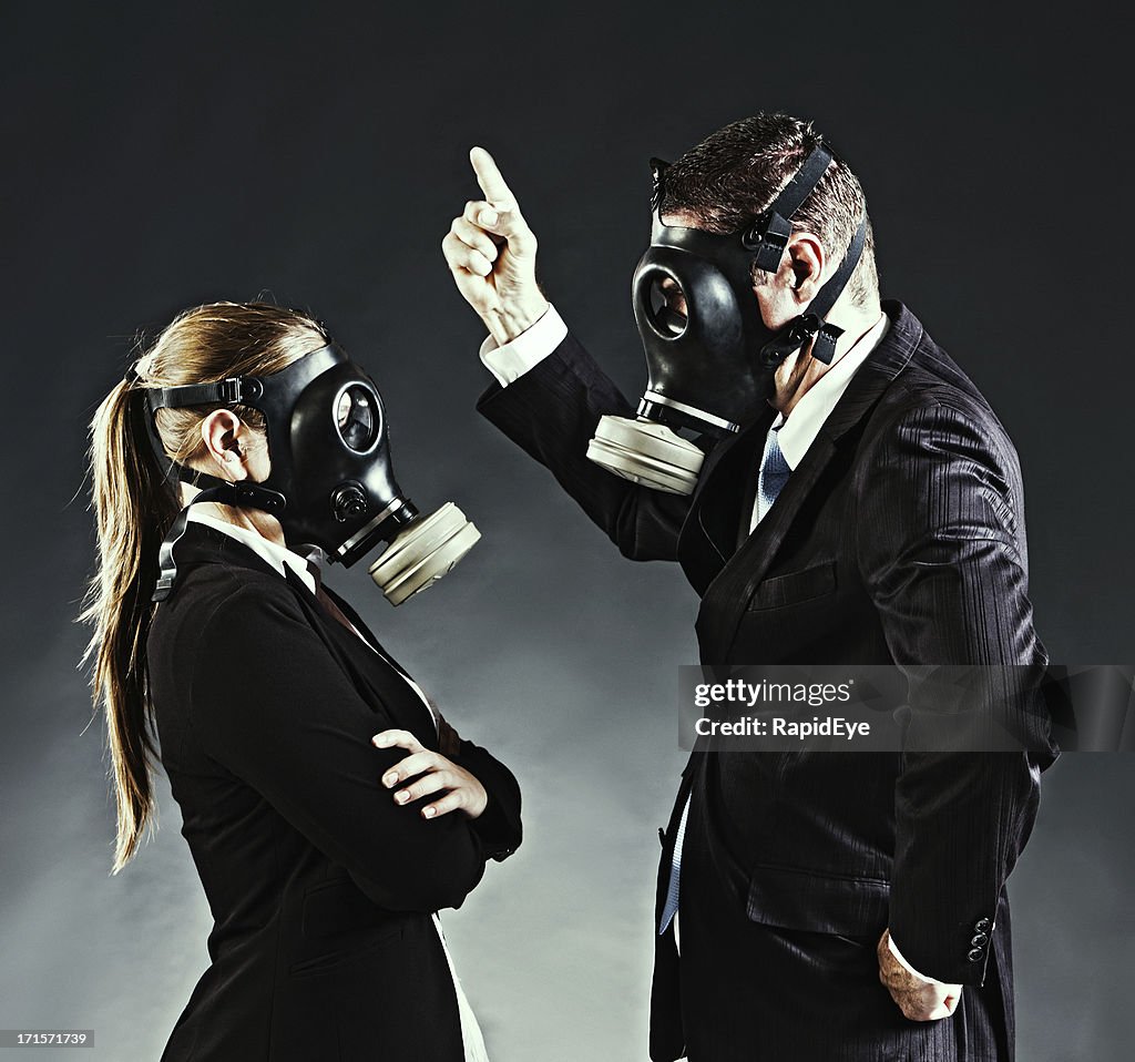 Business couple in gas masks have an argument
