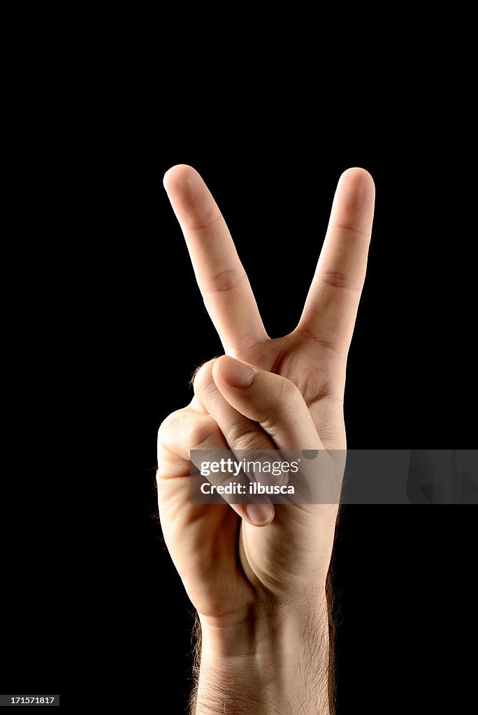 La victoire ou signe de main de la paix isolé sur fond noir