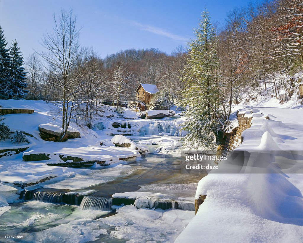 Old-fashioned watermill gristmill and stream in snow