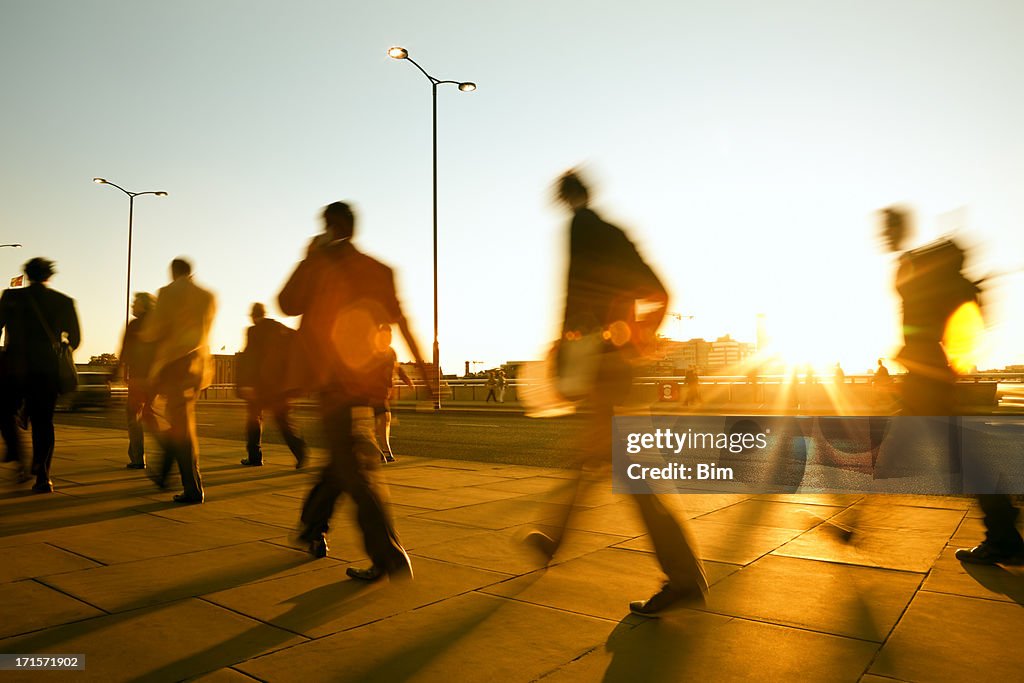 Verschwommene Leute zu Fuß in den Sonnenuntergang