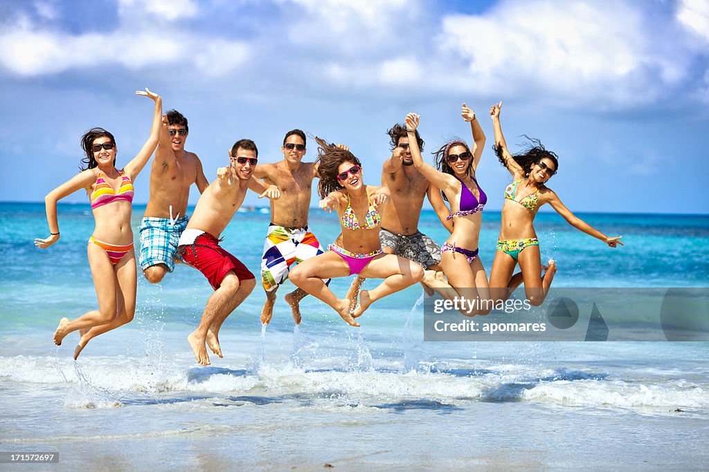 Happy group of young people jumping on a beach party