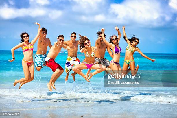 happy group of young people jumping on a beach party - beach party stock pictures, royalty-free photos & images