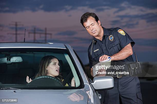 police officer explaining citation to woman driver - highway patrol stockfoto's en -beelden