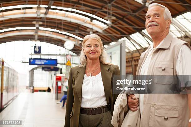 happy senior couple at train station in berlin - man woman train station stockfoto's en -beelden