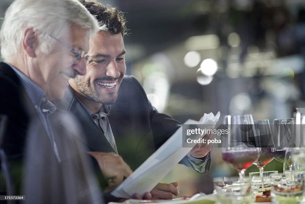 Businesspeople having lunch at restaurant and  studying paperwork