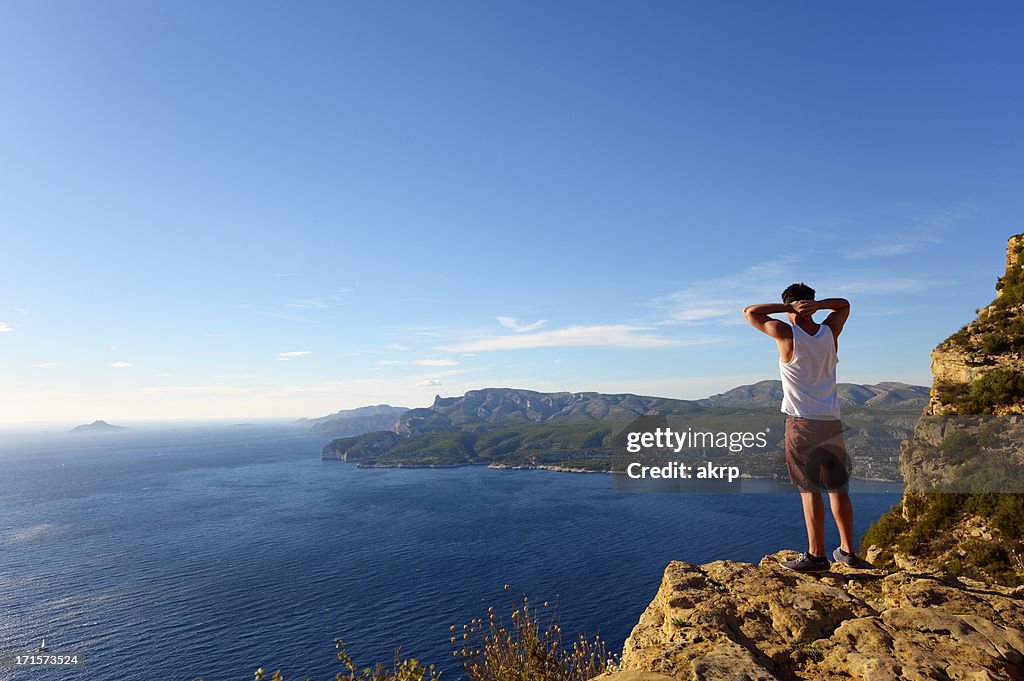 Junger Mann stehend auf steilen Klippe an der Côte D'Azur