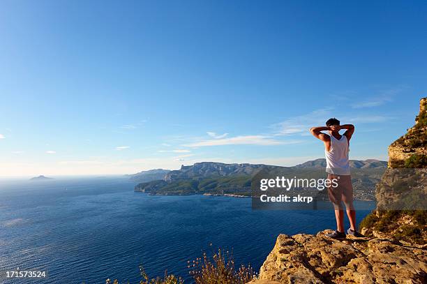 young man standing on steep cliff at the cote d'azur - calanques stock pictures, royalty-free photos & images