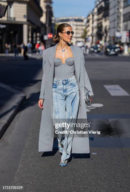 Nina Sandbech wears grey coat, off shoulder top, necklace, sunglasses, denim jeans, blue heels, silver bag outside during the Womenswear...