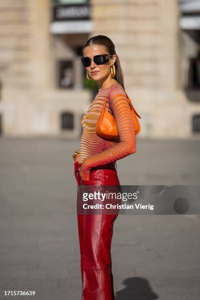 Nina Sandbech wears red leather pants, orange bag, transparent striped orange top, earrings, Miu Miu sunglasses, orange pointed Prada heels outside...