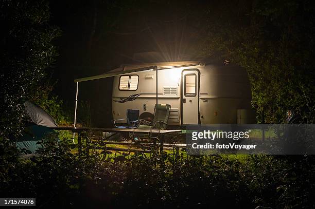 caravan trailer raggiante nella foresta camp sito notte - vehicle trailer foto e immagini stock