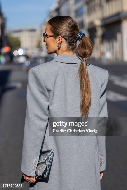 Nina Sandbech wears grey coat, hair piece, earrings, sunglasses, silver bag outside during the Womenswear Spring/Summer 2024 as part of Paris Fashion...
