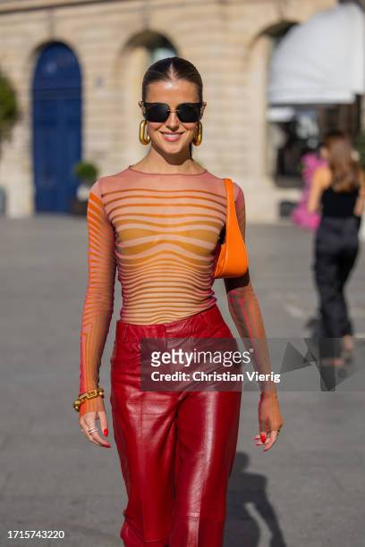 Nina Sandbech wears red leather pants, orange bag, transparent striped orange top, earrings, Miu Miu sunglasses outside during the Womenswear...