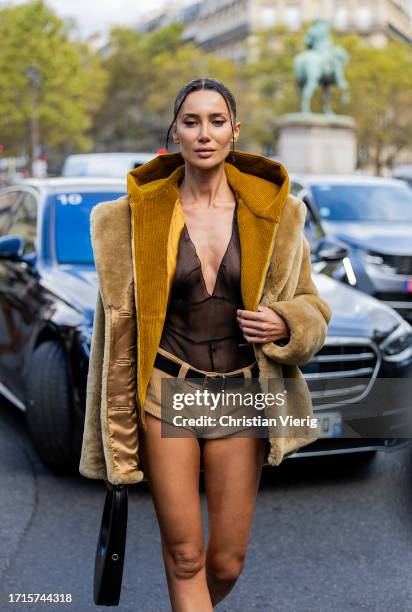 Sabina Jakubowicz wears black transparent top, beige shorts, beige hooded teddy fur jacket, black bag, pointed heels outside Miu Miu during the...