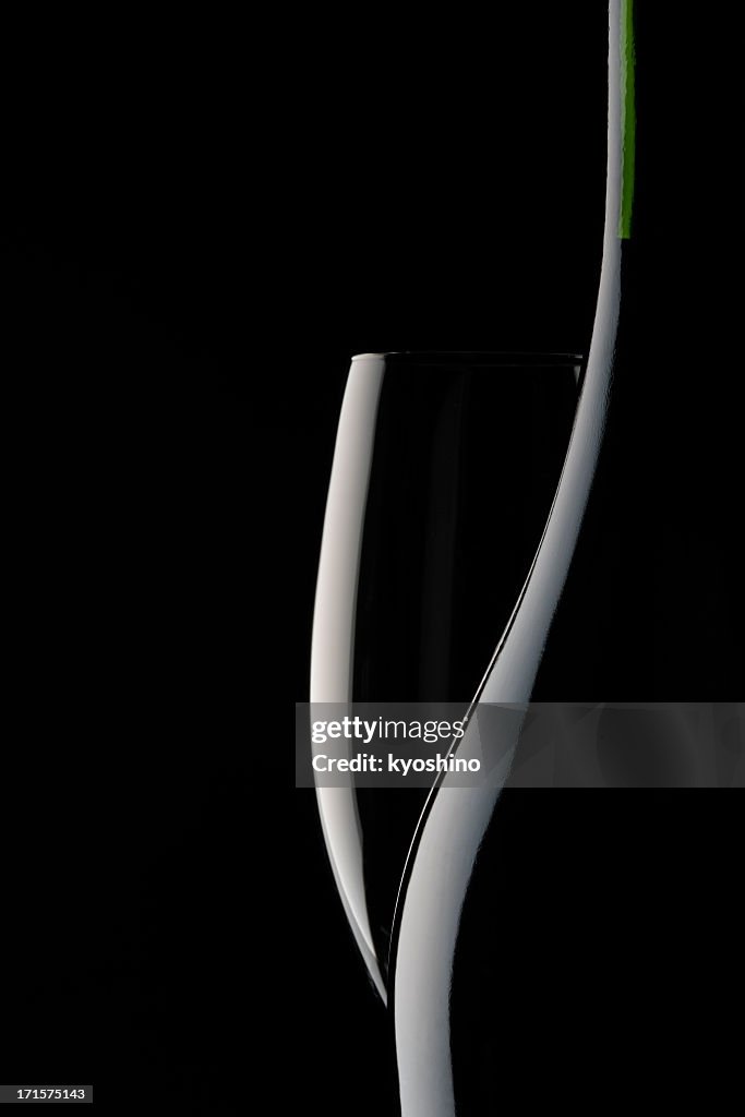 Leere Glas Champagner und leere Flasche vor schwarzem Hintergrund