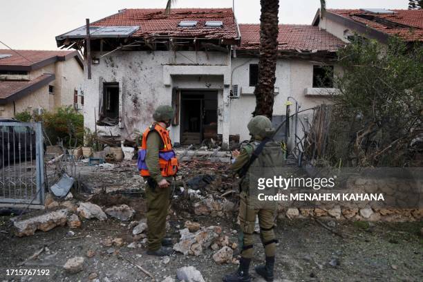 Israeli troops inspect a damaged house in the southern Israeli city of Ashkelon after a rocket attack from Gaza on October 9, 2023. Stunned by the...