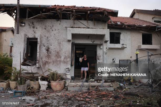 Woman stands at the entrance of a damaged house in the southern Israeli city of Ashkelon after a rocket attack from Gaza on October 9, 2023. Stunned...