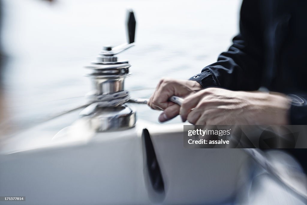 Mãos de homem trabalhando em uma winch durante sailturn