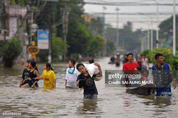 Local residents make their way through a flooded street after heavy rains in Bago township in Myanmar's Bago region on October 9, 2023. / "The...