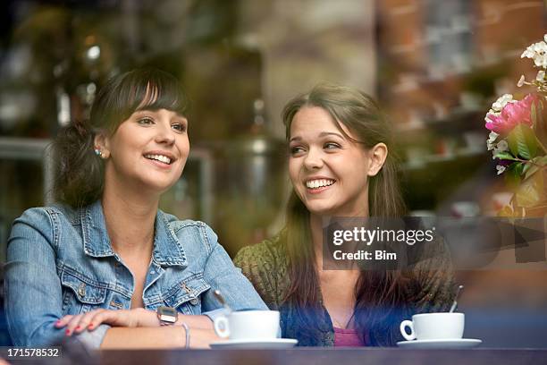 two beautiful women sitting in cafe, smiling, view through glass - bar girl stock pictures, royalty-free photos & images