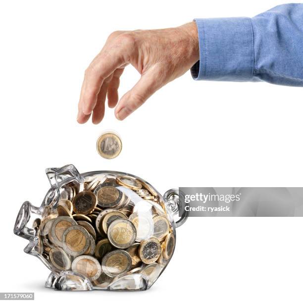 elderly hand dropping euro coin into full savings bank isolated - hands full stock pictures, royalty-free photos & images