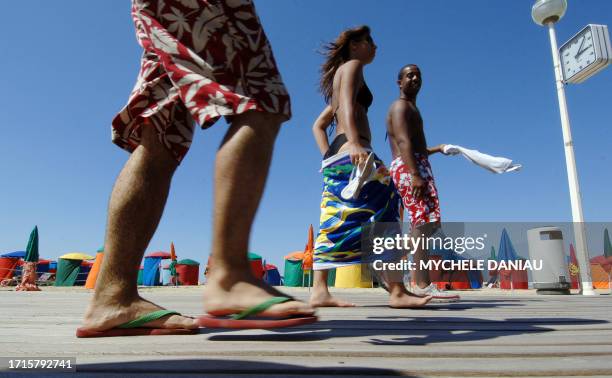 Des vacanciers marchent le 04 août 2007 sur les planches de la plage de Deauville, où le week-end s'annonce ensoleillé. Les Français restent cette...