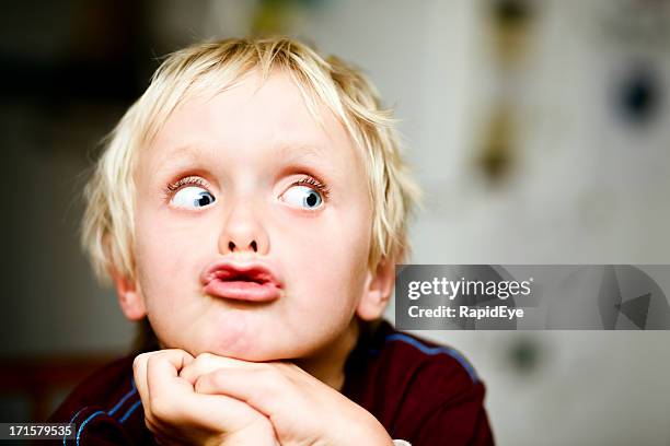 siete-year-old boy rolls sus ojos a la derecha - suspicion fotografías e imágenes de stock