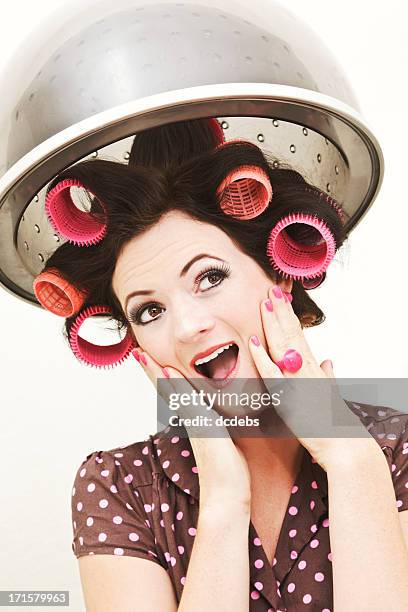 retro-styled young woman in curlers under salon hairdryer - vintage beauty salon stock pictures, royalty-free photos & images