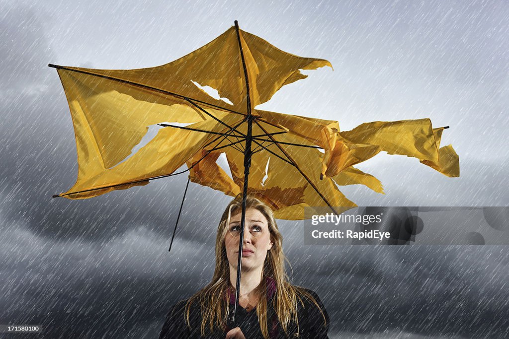 Wunderschöne unglücklicher blonde mit zerstört Regenschirm es eingewickelt in Gewitter