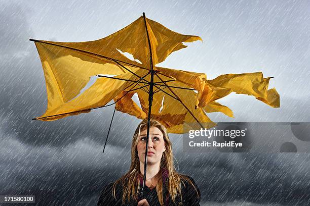 beautiful unhappy blonde with ruined umbrella getting soaked in thunderstorm - rainy day stockfoto's en -beelden