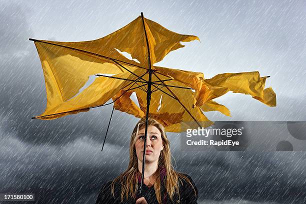 beautiful unhappy blonde with ruined umbrella getting soaked in thunderstorm - damaged stock pictures, royalty-free photos & images