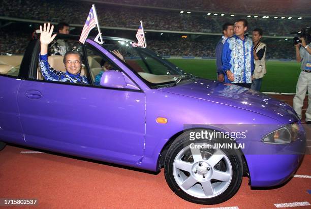Malaysian Prime Minister Mahathir Mohamad waves to the crowd while driving a Malaysian prototype convertible car into the National Stadium in Bukit...