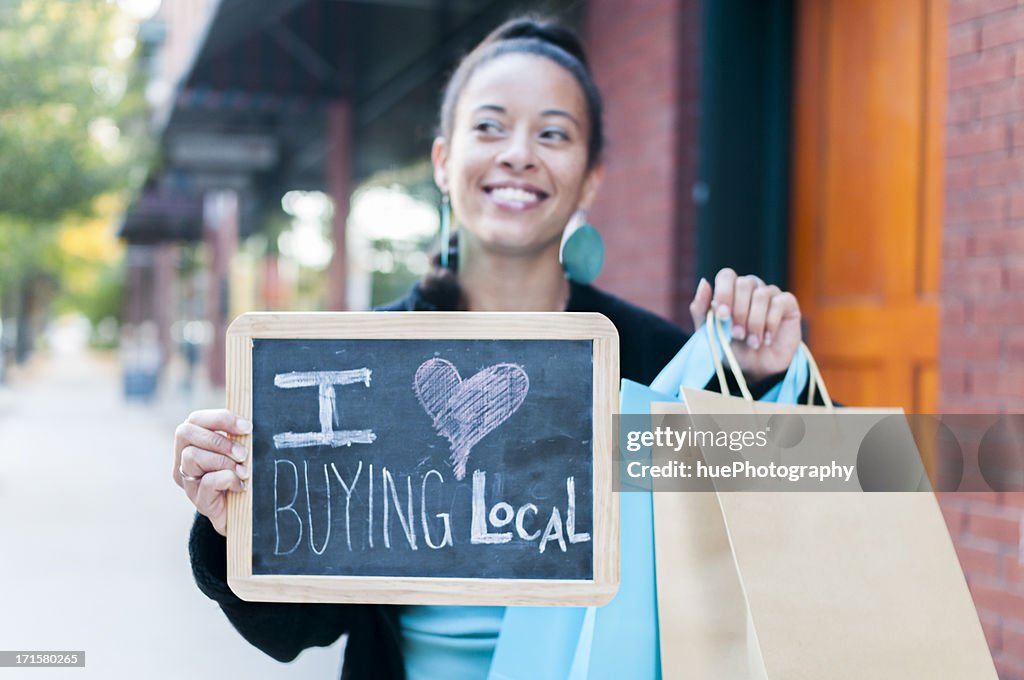 Woman holding sign that says I love buying local 