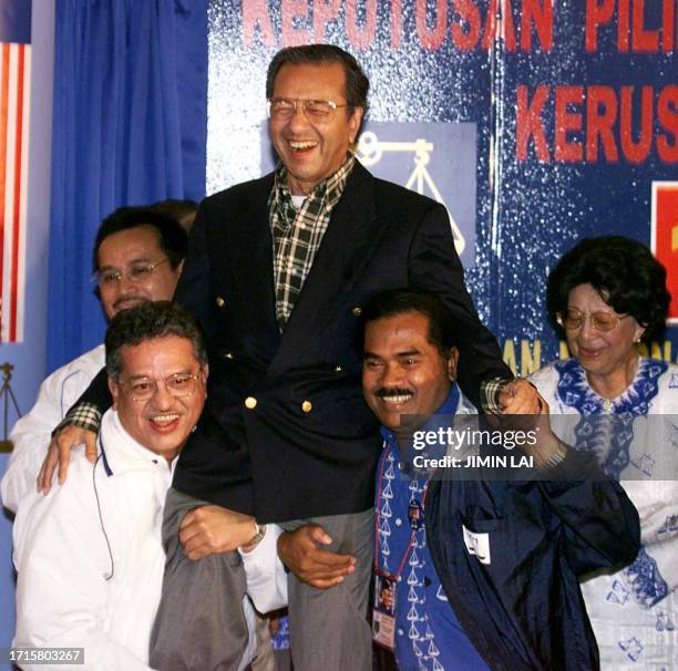 Malaysian Prime Minister Mahathir Mohamad is carried by supporters, while his wife Siti Hasmah reacts 30 November 1999 at the results centre in Kuala...