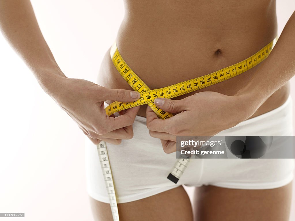 Woman measuring hips with tape measure.