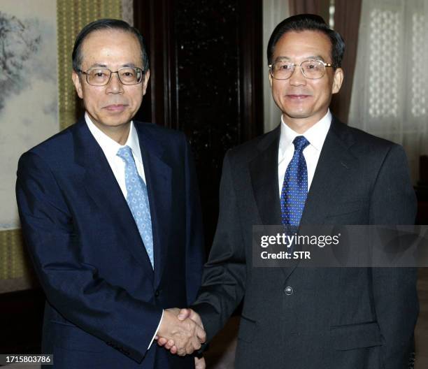 Japanese Chief Cabinet Secretary Yasuo Fukuda shakes hands with Chinese Prime Minister Wen Jiabao at the Zhongnanhai leadership compound in Beijing,...