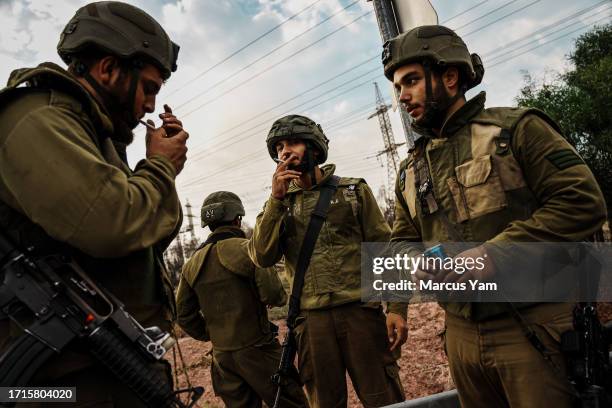 Israeli soldiers take a break after taking shelter during a counter barrage from the Iron Dome defenses near Mavki'im, Israel, Monday, Oct. 9, 2023....