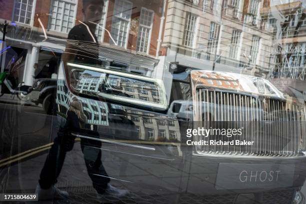 Members of the public walk past the window of the Rolls-Royce car showroom in Mayfair where a 'Ghost' model is displayed in the dealership's window,...