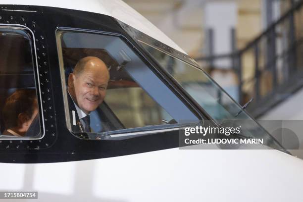 German Chancellor Olaf Scholz smiles from the cockpit as he inspects an Airbus A321 neo jet with French President Emmanuel Macron at the Airbus plant...