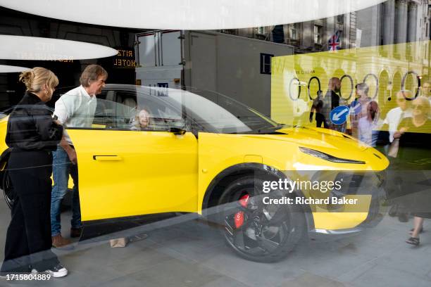 Reflections of passers-by and potential buyers looking at a Lotus 'Eletre' EV car which is positioned in the window of the brand's showroom on...